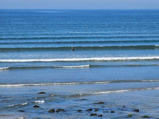 Surfer paddling for a 1 foot wave on the beach